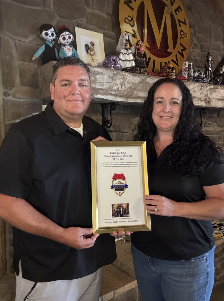 Two people holding winery award certificate
