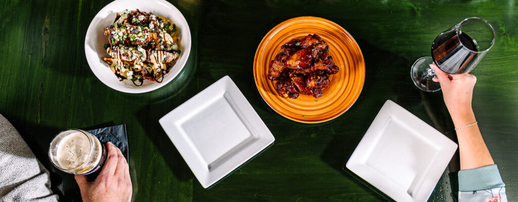 Top-down view of wings, salad, beer and wine