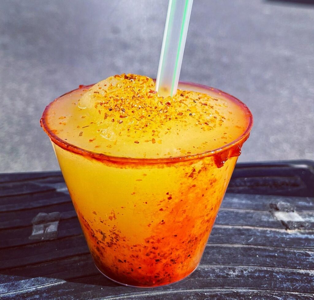 Mango chamoy drink in clear cup with straw.