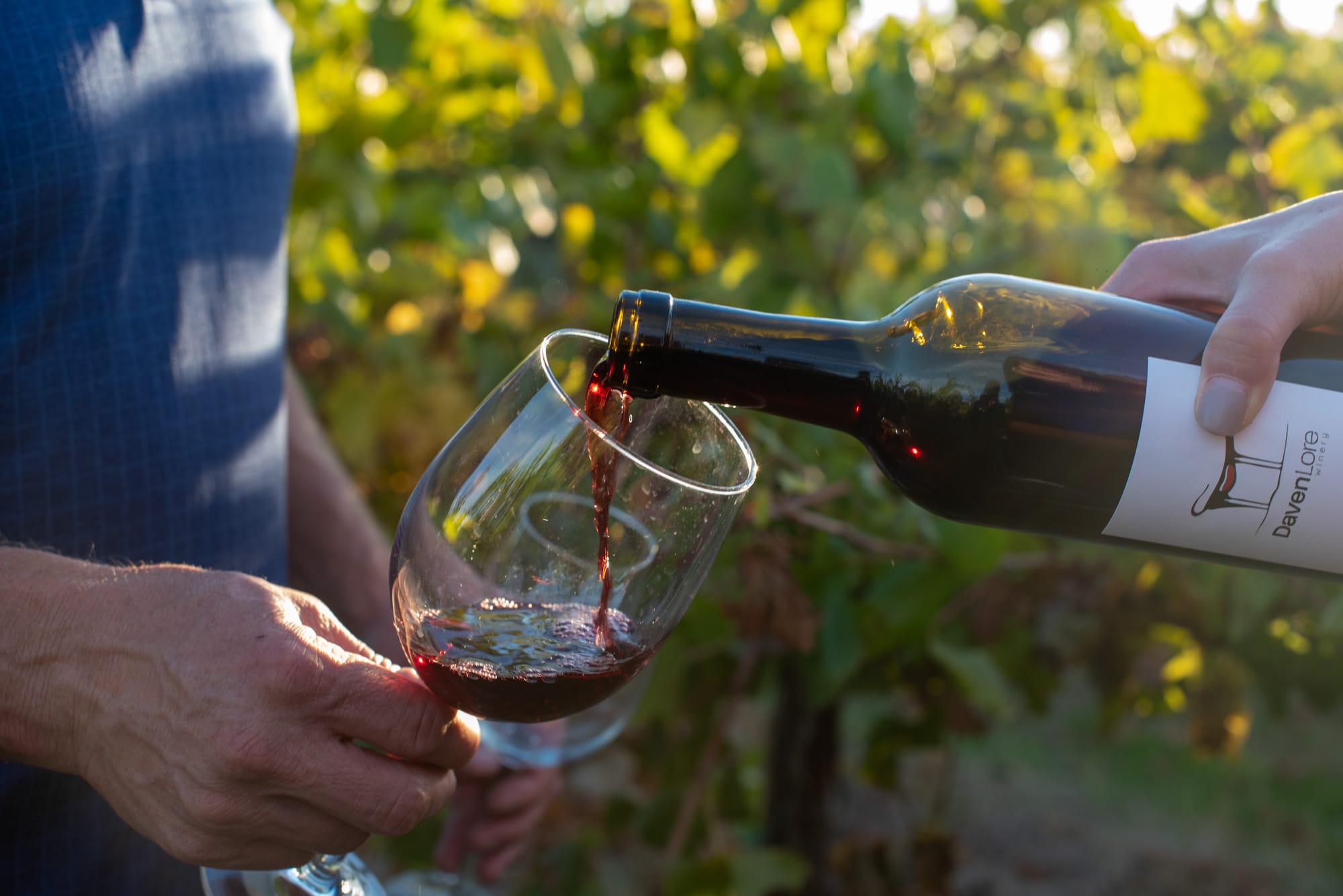 Pouring red wine into a glass outdoors.