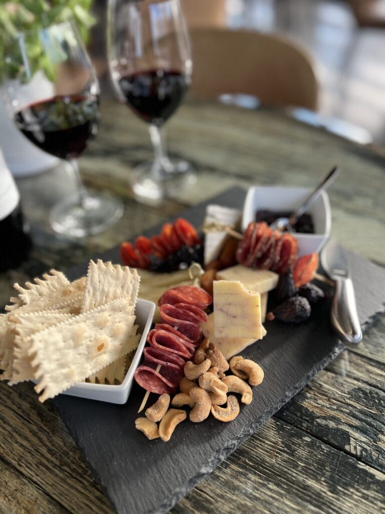 Charcuterie board with wine on rustic table.