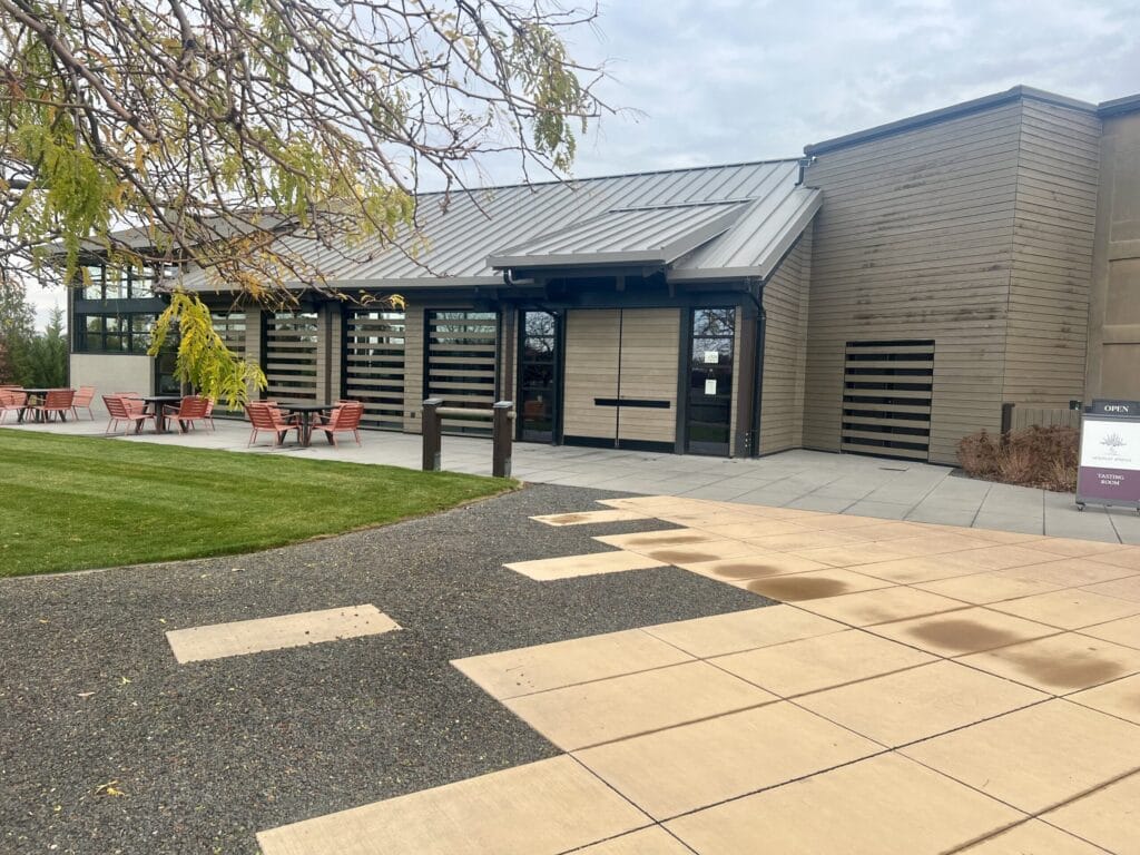 Modern building with outdoor seating and green lawn.