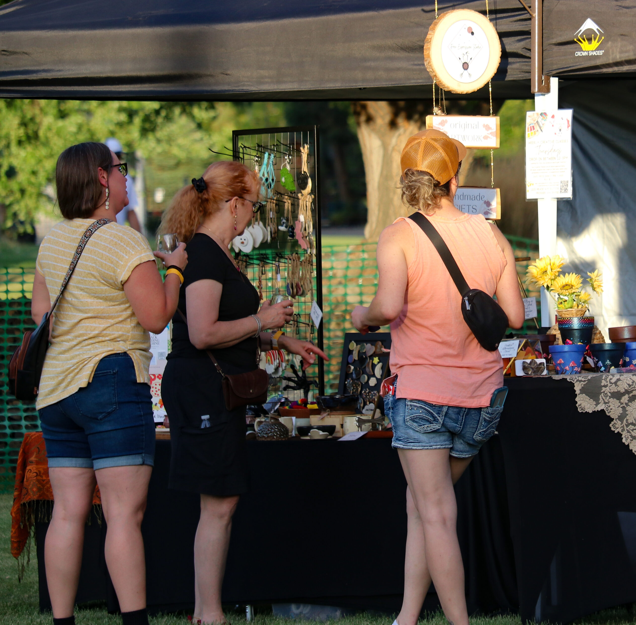 People shopping at an outdoor craft market stall.