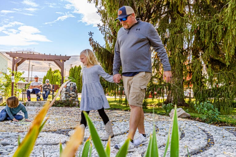 Man and girl walking hand in hand outside.