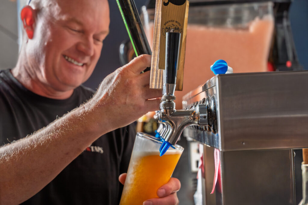 Person pouring draft beer from tap