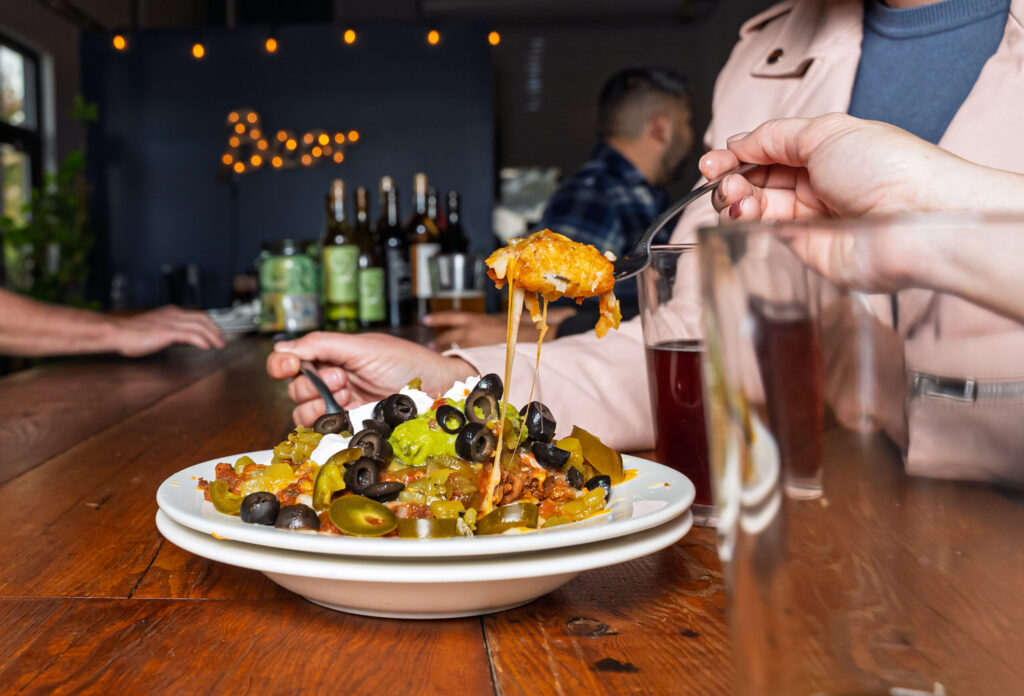 Cheesy nachos with black olives, jalapeños, and drinks.