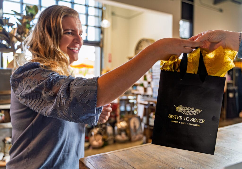 Woman receives gift bag at boutique counter.