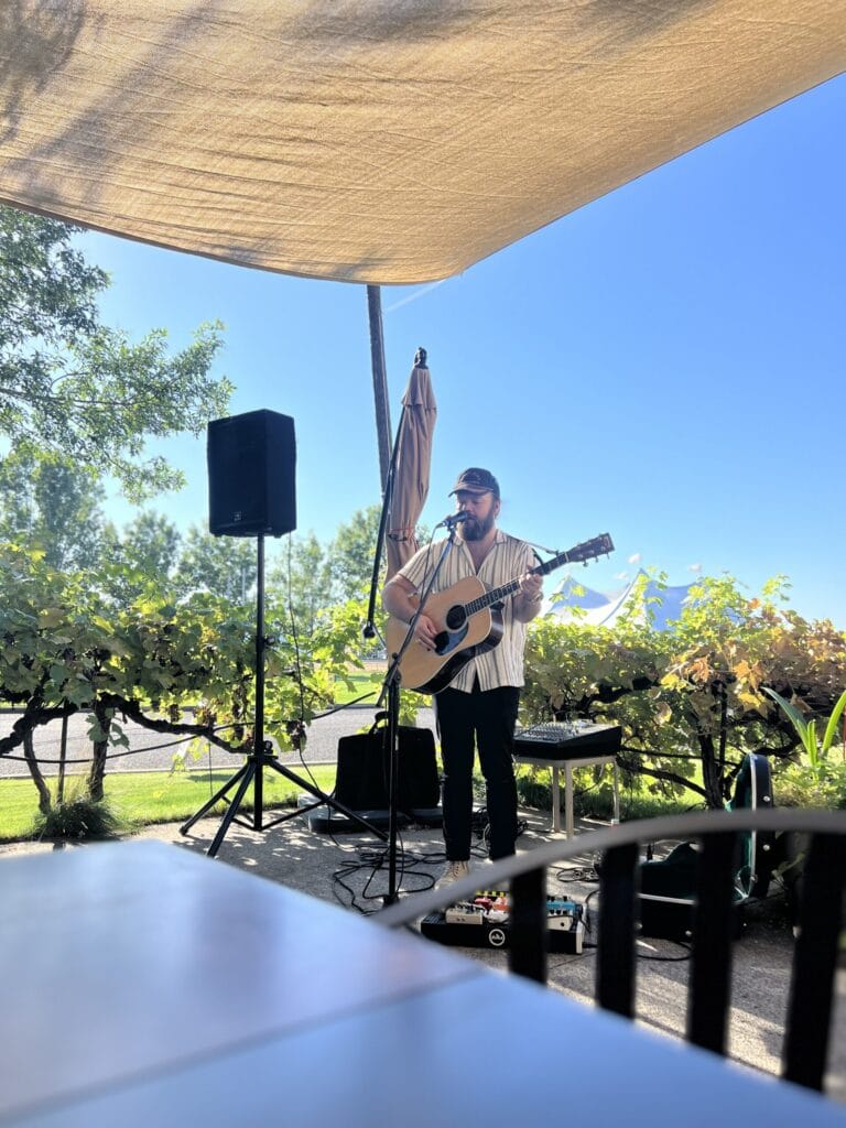Guitarist performing outdoors under sunshade
