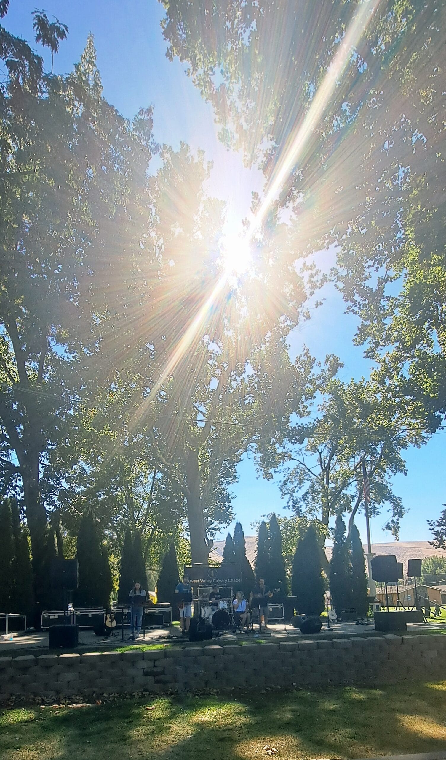 Band performing in sunny outdoor park setting.