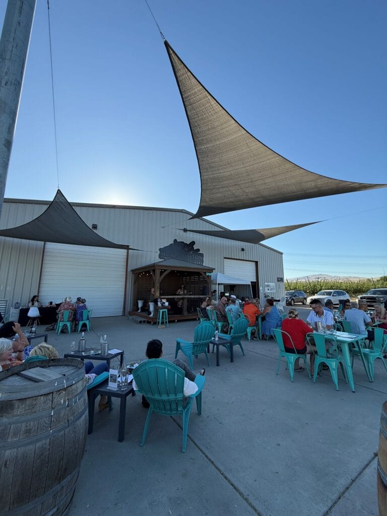 Outdoor brewery with shaded seating area and visitors.