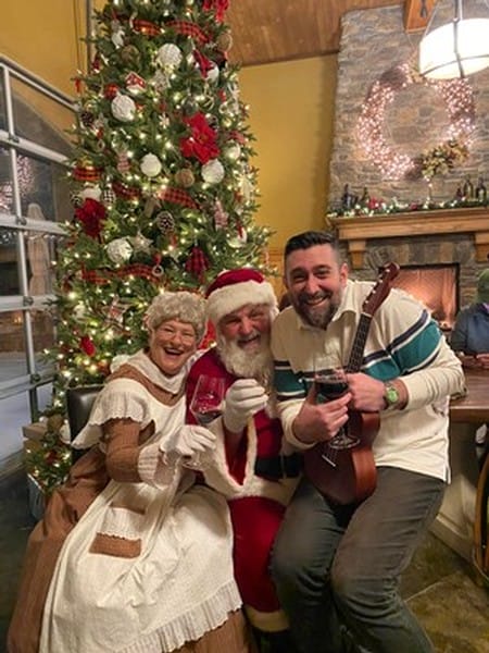 Festive gathering by Christmas tree with Santa and guitar.