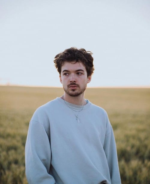 Person standing in field with blue sweatshirt.