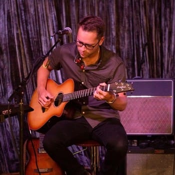 Musician playing acoustic guitar on stage