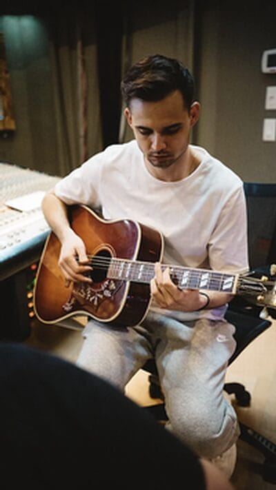 Man playing acoustic guitar in recording studio.