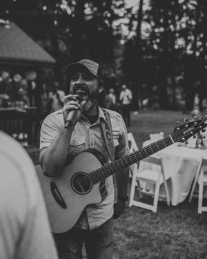 Musician singing outdoors with acoustic guitar