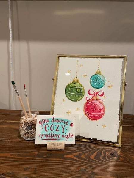 Framed Christmas ornaments art with paintbrushes.