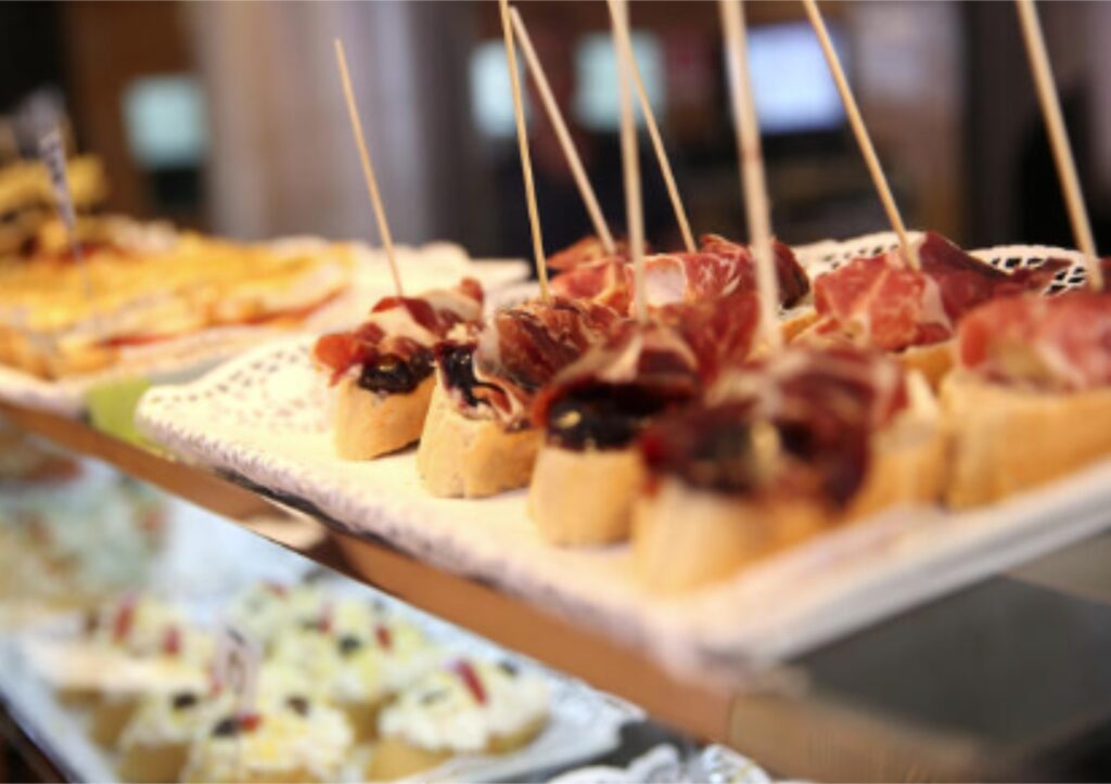 Spanish tapas with cured meats on bread slices.