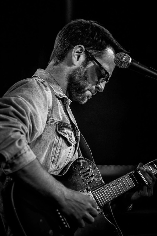 Guitarist performing live on stage in black and white.