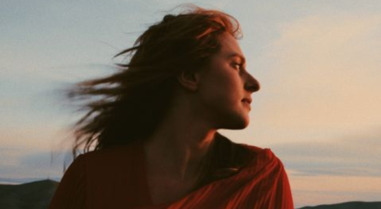 Person gazing at sunset with windblown hair.