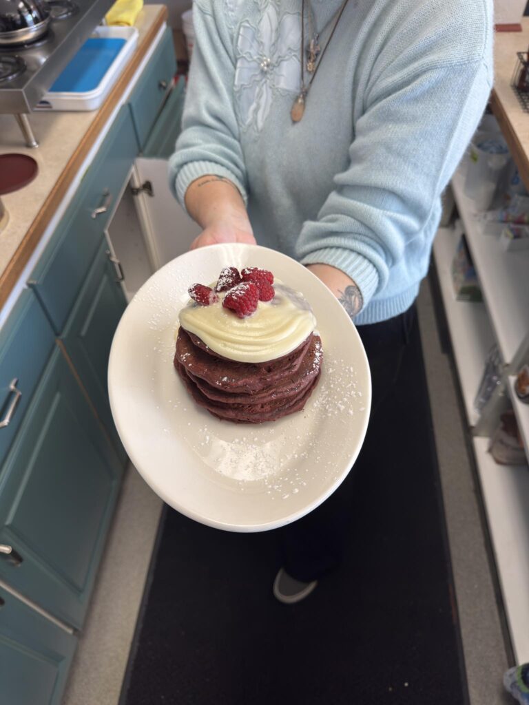 Stack of red pancakes with cream and raspberries