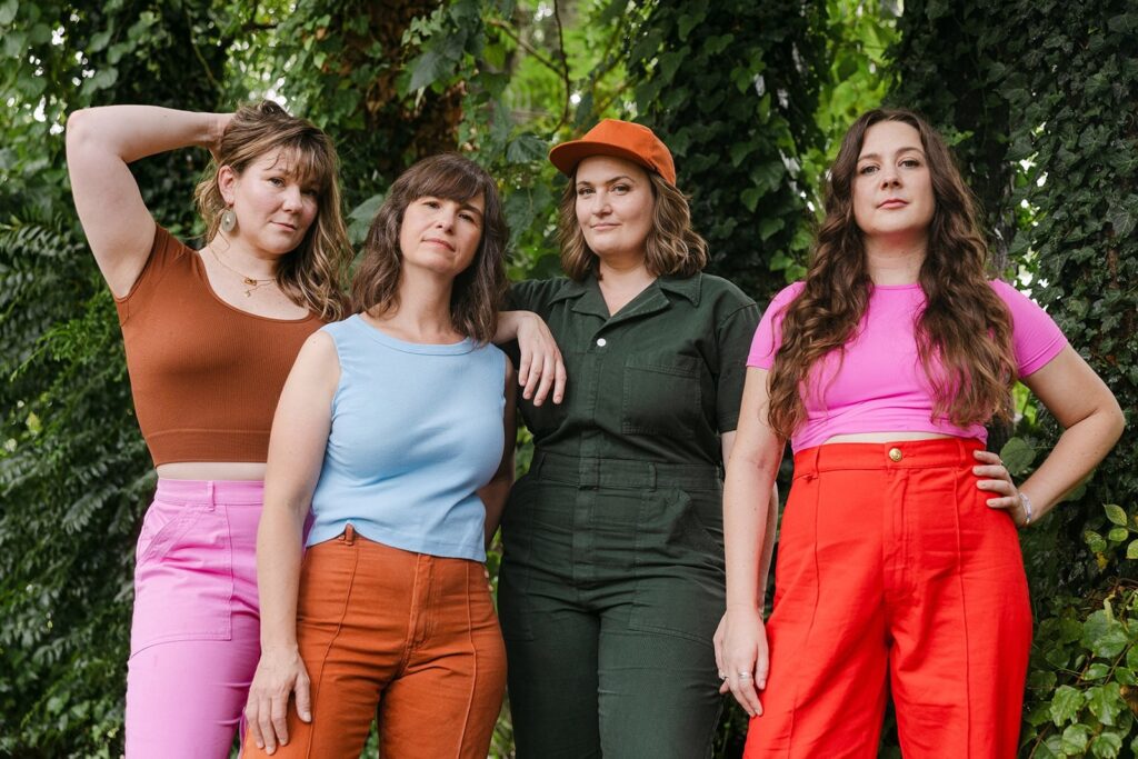 Four women posing confidently outdoors in colorful outfits