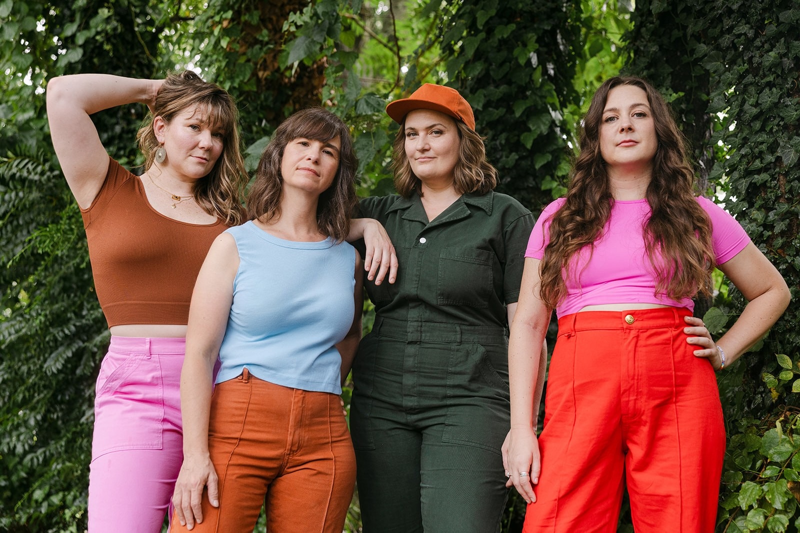 Four women posing confidently outdoors in colorful outfits