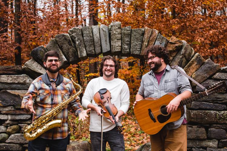 Three musicians under stone arch in autumn