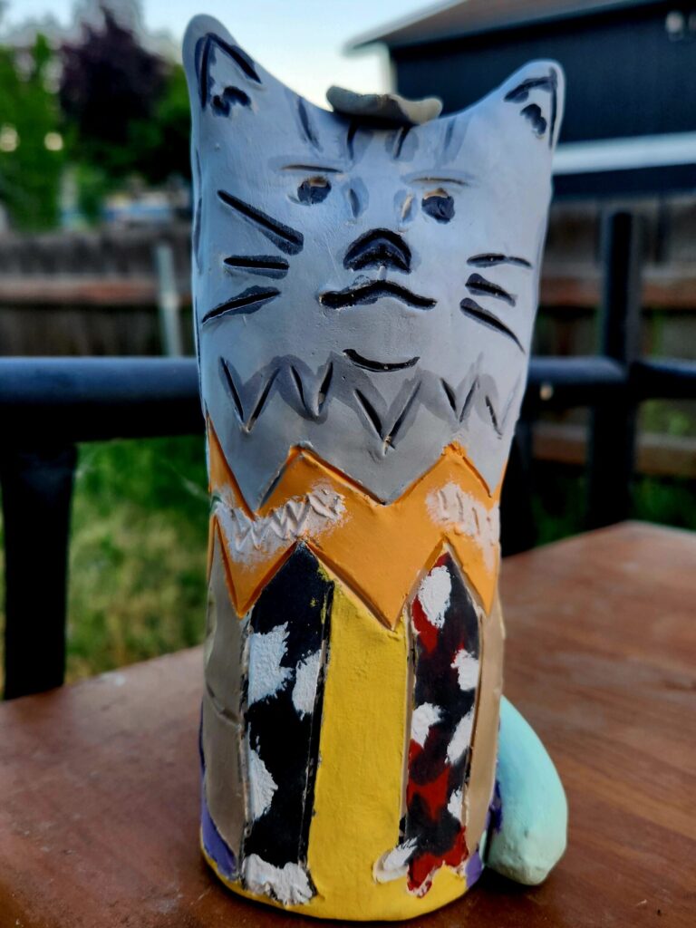 Hand-painted wooden cat figurine on outdoor table
