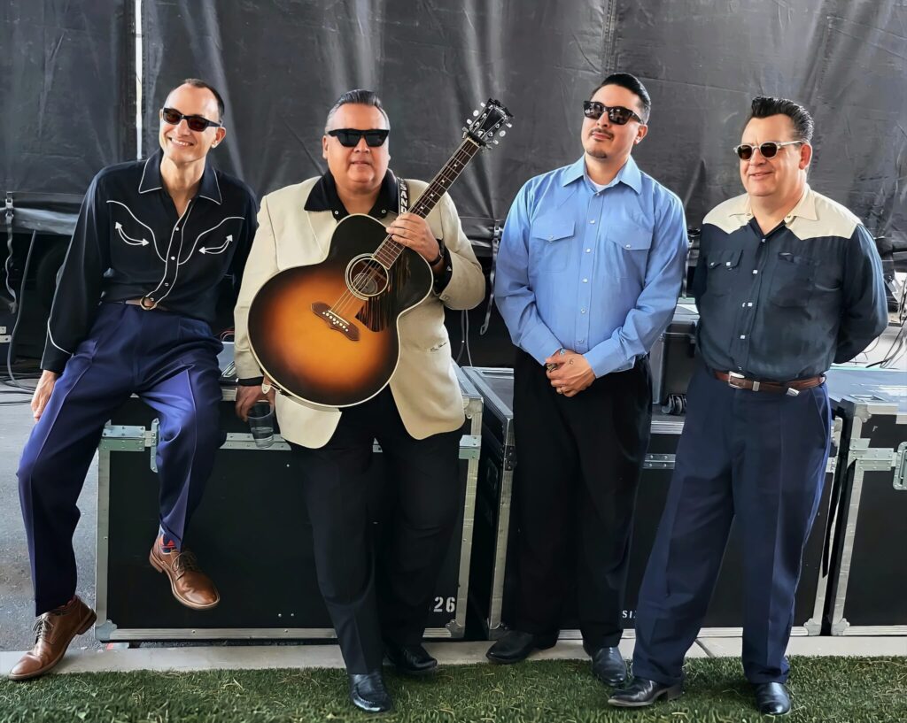 Four musicians backstage with acoustic guitar