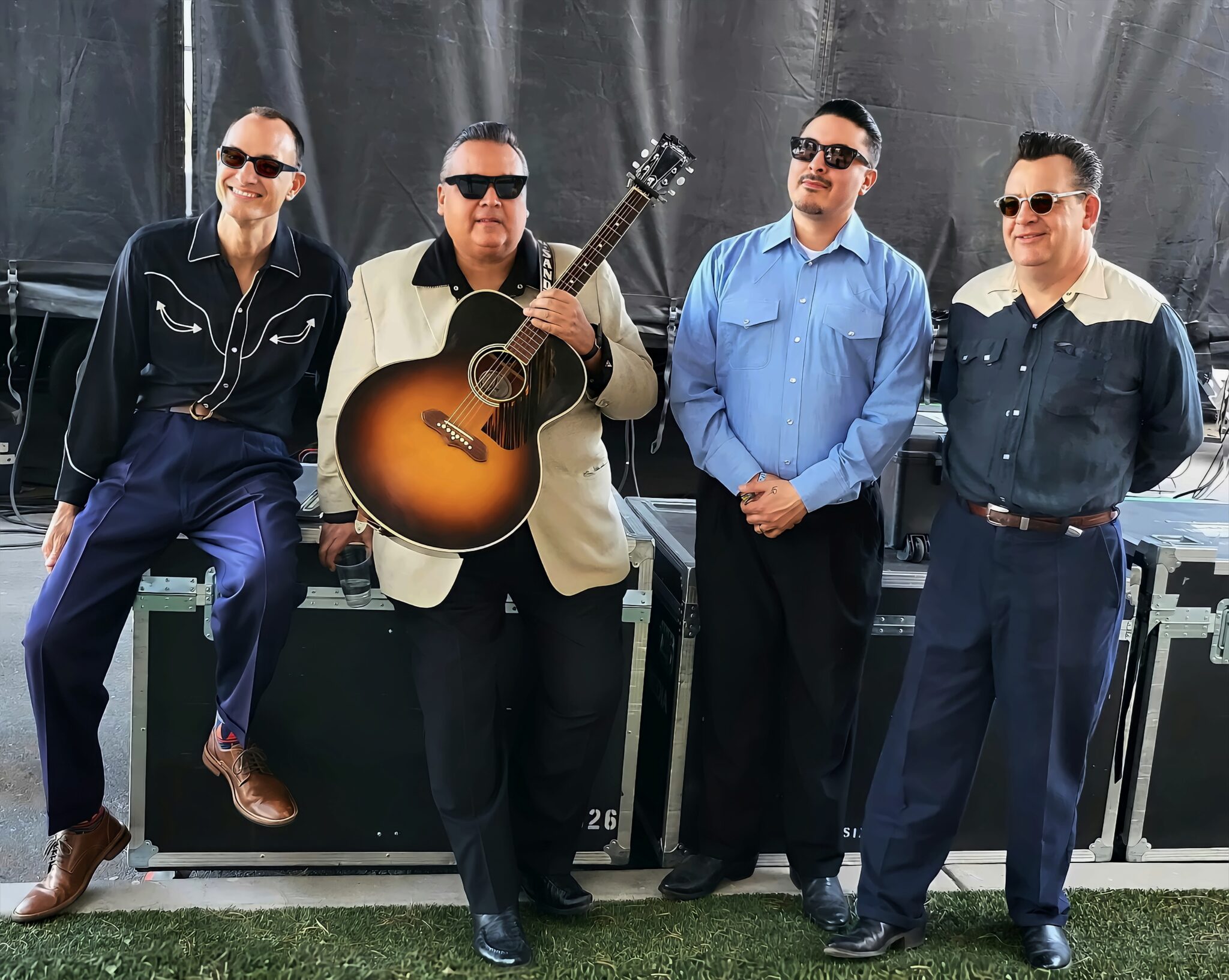 Four musicians backstage with acoustic guitar