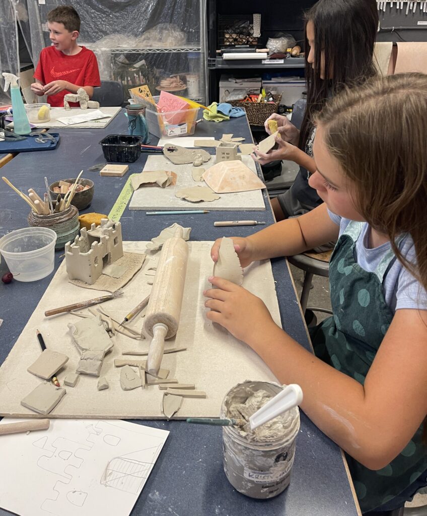 Children sculpting clay projects in art classroom