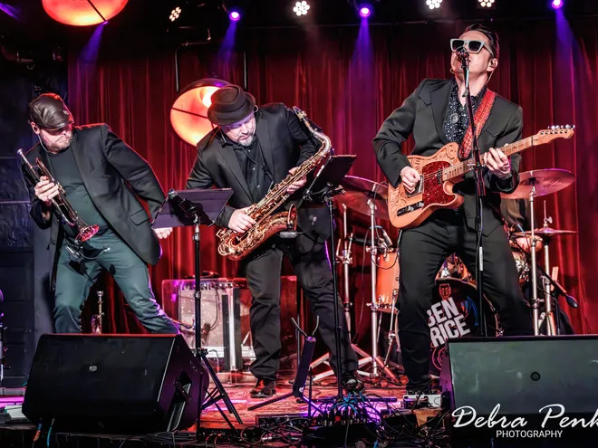Live band performing on stage with horns and guitar