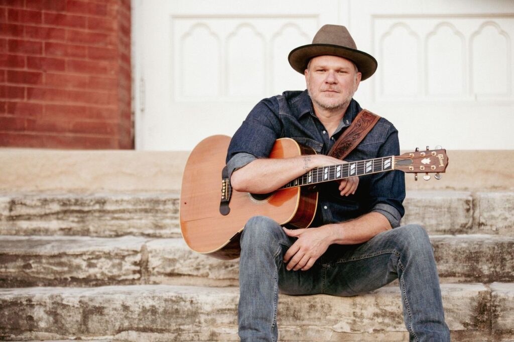 Man with acoustic guitar sitting on stone steps