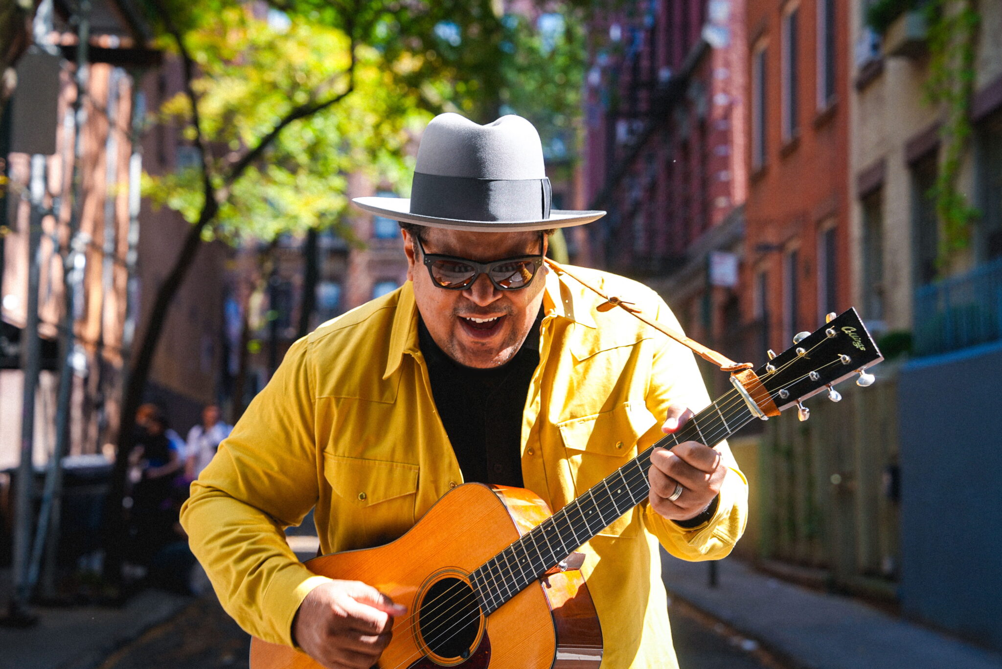 Man in yellow jacket playing guitar on city street