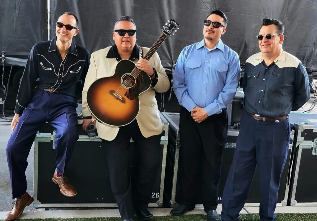 Four musicians backstage with acoustic guitar
