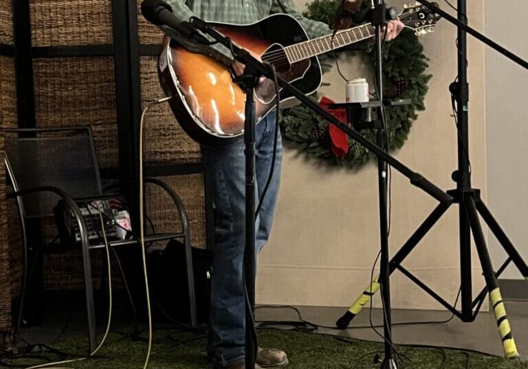 Man performing music with guitar and microphone