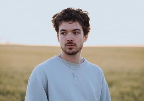 Person standing in field with blue sweatshirt.