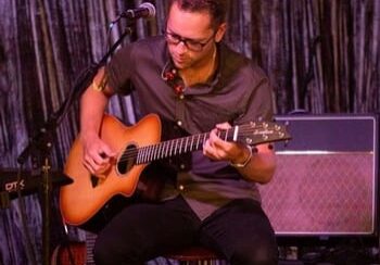 Musician playing acoustic guitar on stage