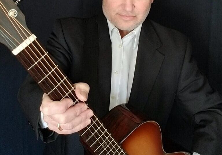 Man in suit holding acoustic guitar