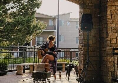 Woman playing guitar at outdoor venue, sunny afternoon.