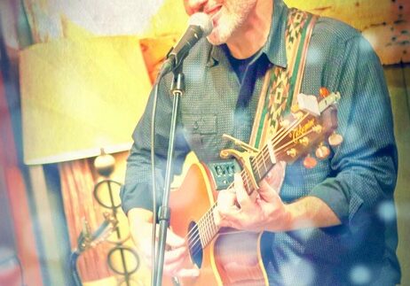 Man playing acoustic guitar and singing on stage.