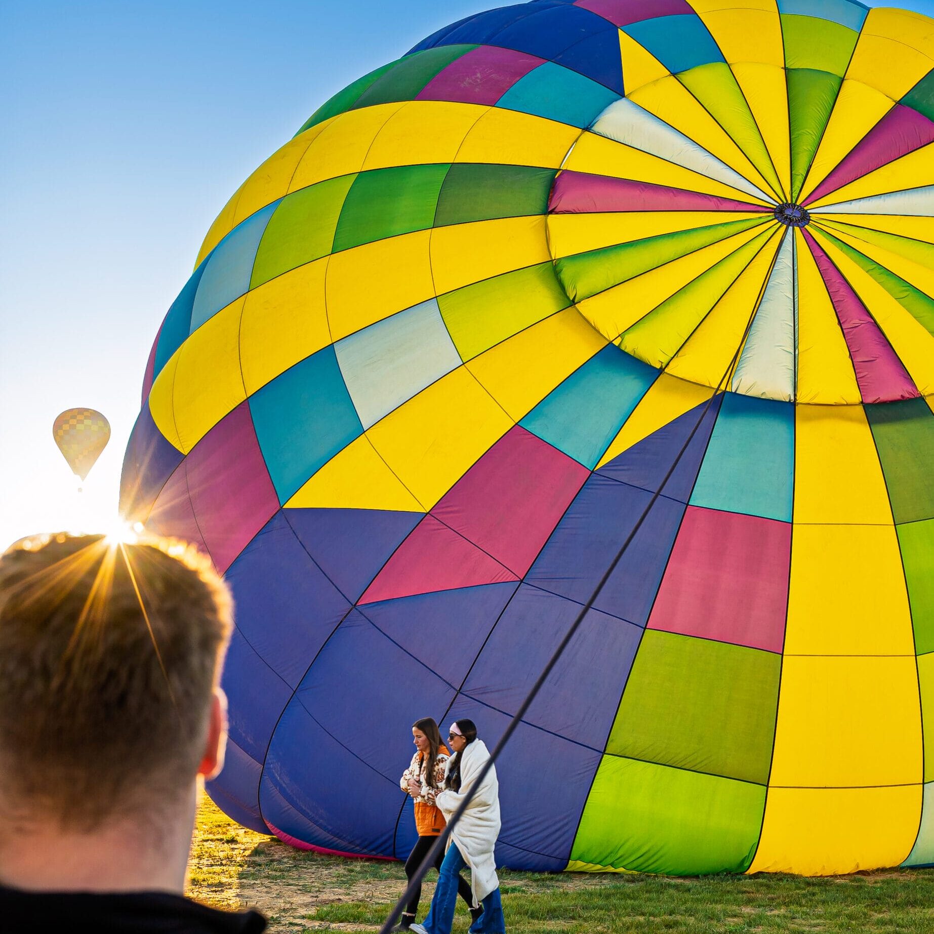 Colorful hot air balloon inflated on field.