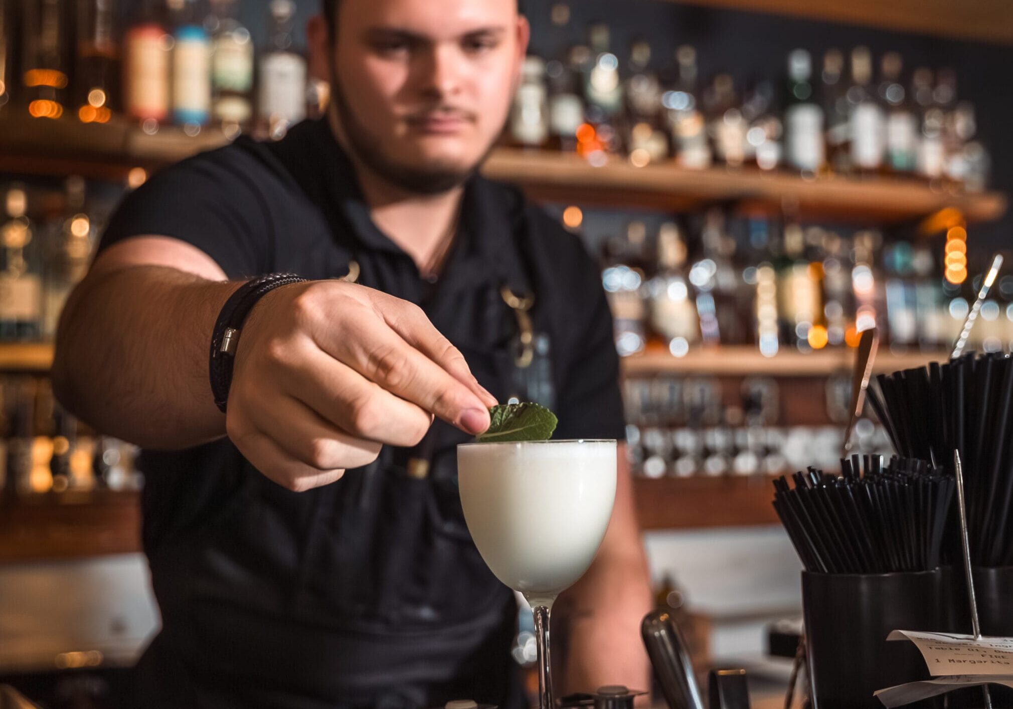 Bartender garnishing cocktail at bar.