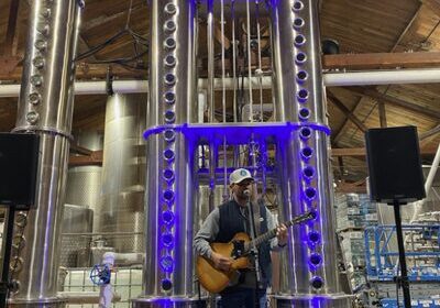 Musician playing guitar in an industrial distillery setting.