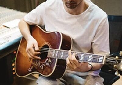 Man playing acoustic guitar in recording studio.