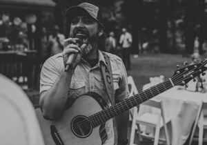 Musician singing outdoors with acoustic guitar