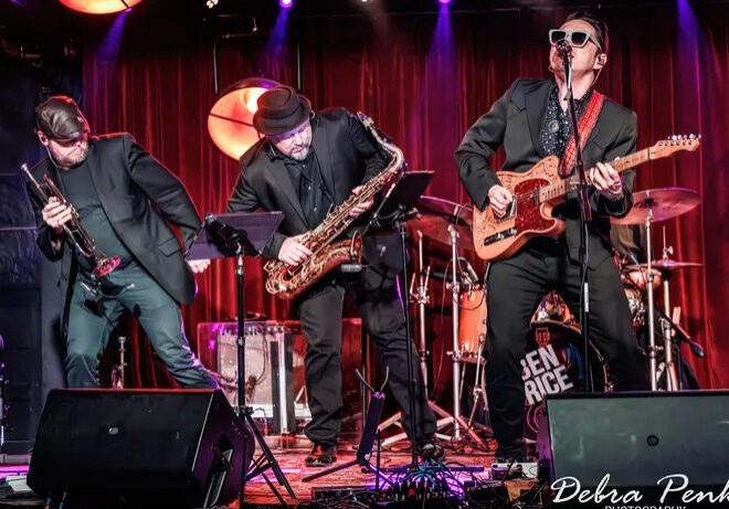 Live band performing on stage with horns and guitar