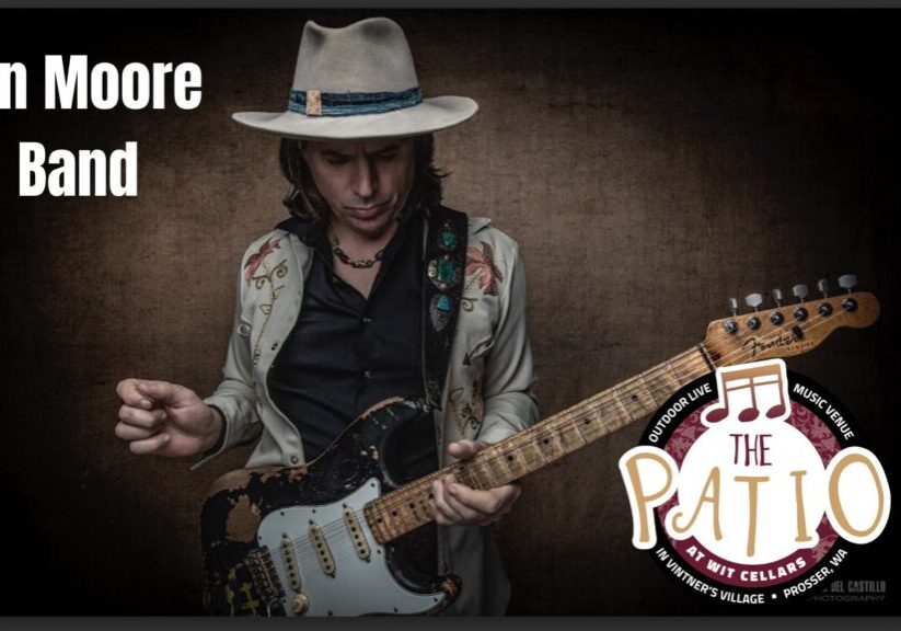 Musician playing electric guitar with Ian Moore Band text