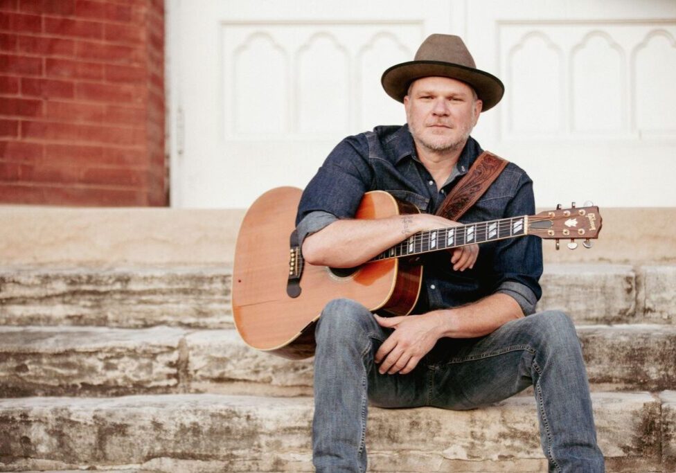 Man with acoustic guitar sitting on stone steps