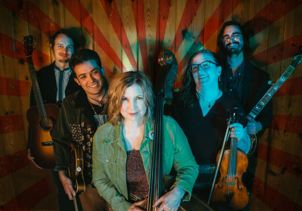 Group of musicians with instruments against striped background.
